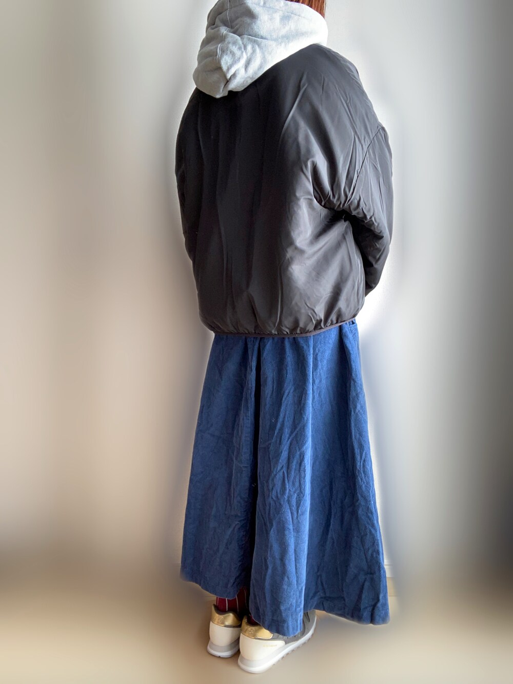 ベージュ系のブルゾン、グレー系のパーカー、ブルー系のスカートを着用したレディースの冬コーディネートの3枚目の写真