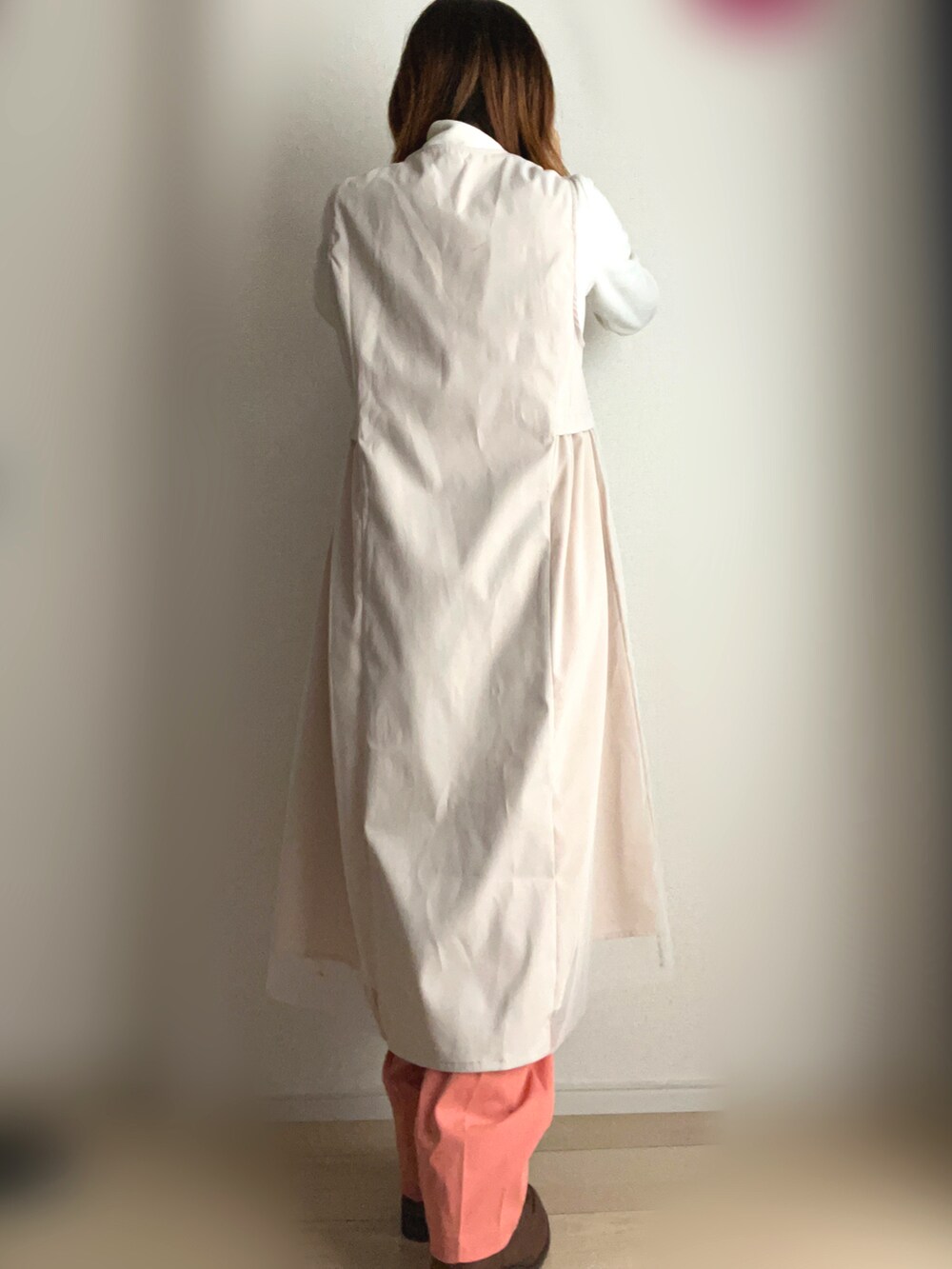 オレンジ系のその他パンツ、ベージュ系のベストを着用したレディースの秋コーディネートの2枚目の写真