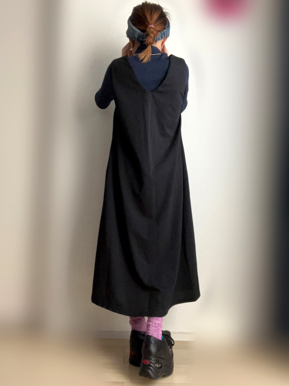 ブラック系のジャンパースカート、ブラック系のスニーカーを着用したレディースの秋コーディネートの2枚目の写真
