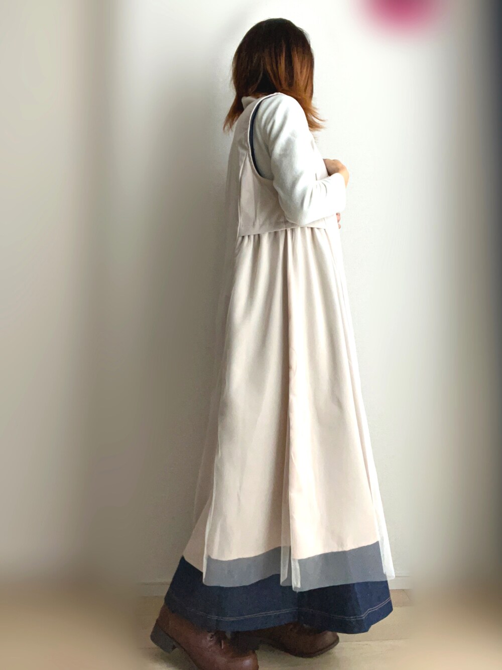 ベージュ系のベスト、ブルー系のワンピースを着用したレディースの秋コーディネートの2枚目の写真