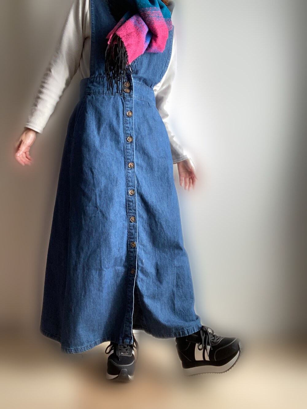 ブルー系のジャンパースカート、ブラック系のスニーカーを着用したレディースの冬コーディネートの2枚目の写真