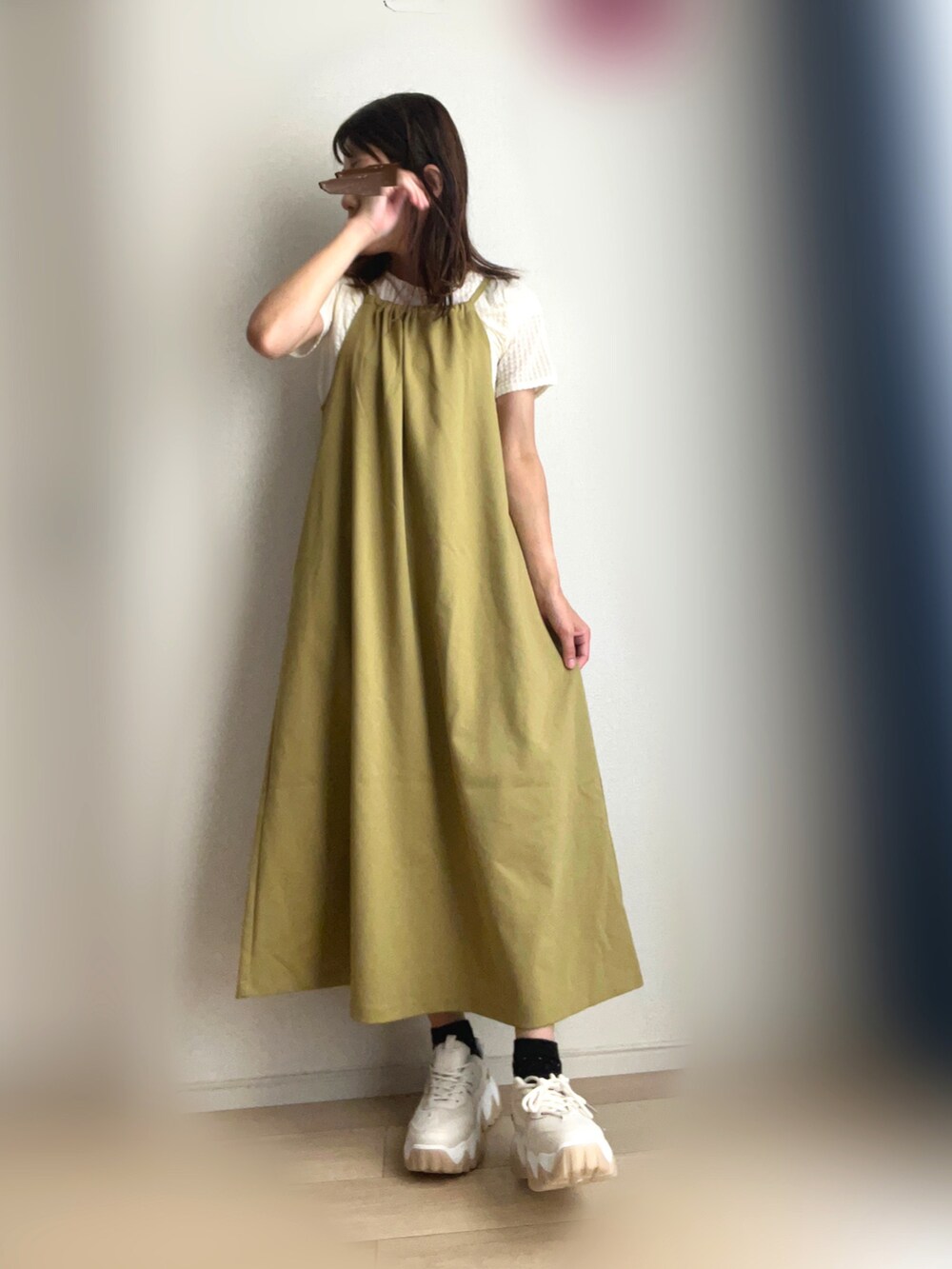 グリーン系のワンピース、ベージュ系のスニーカーを着用したレディースの秋コーディネートの2枚目の写真