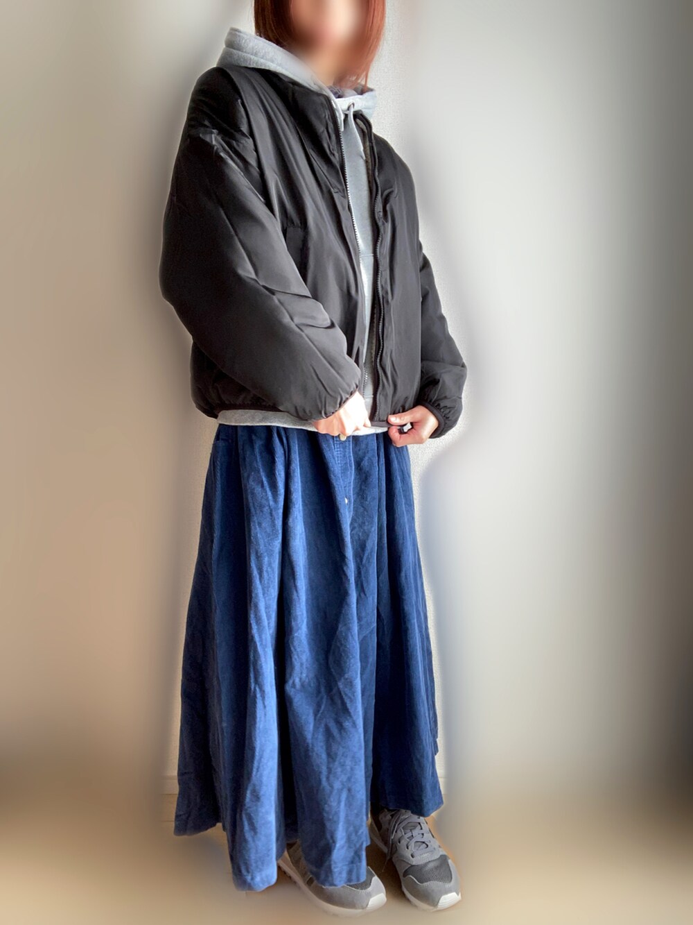 ベージュ系のブルゾン、グレー系のパーカー、ブルー系のスカートを着用したレディースの冬コーディネートの2枚目の写真