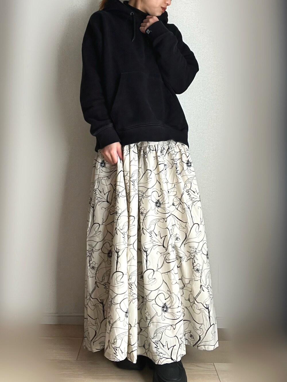 ホワイト系のスカート、ベージュ系のベスト、ブラック系のスニーカーを着用したレディースの冬コーディネートの3枚目の写真