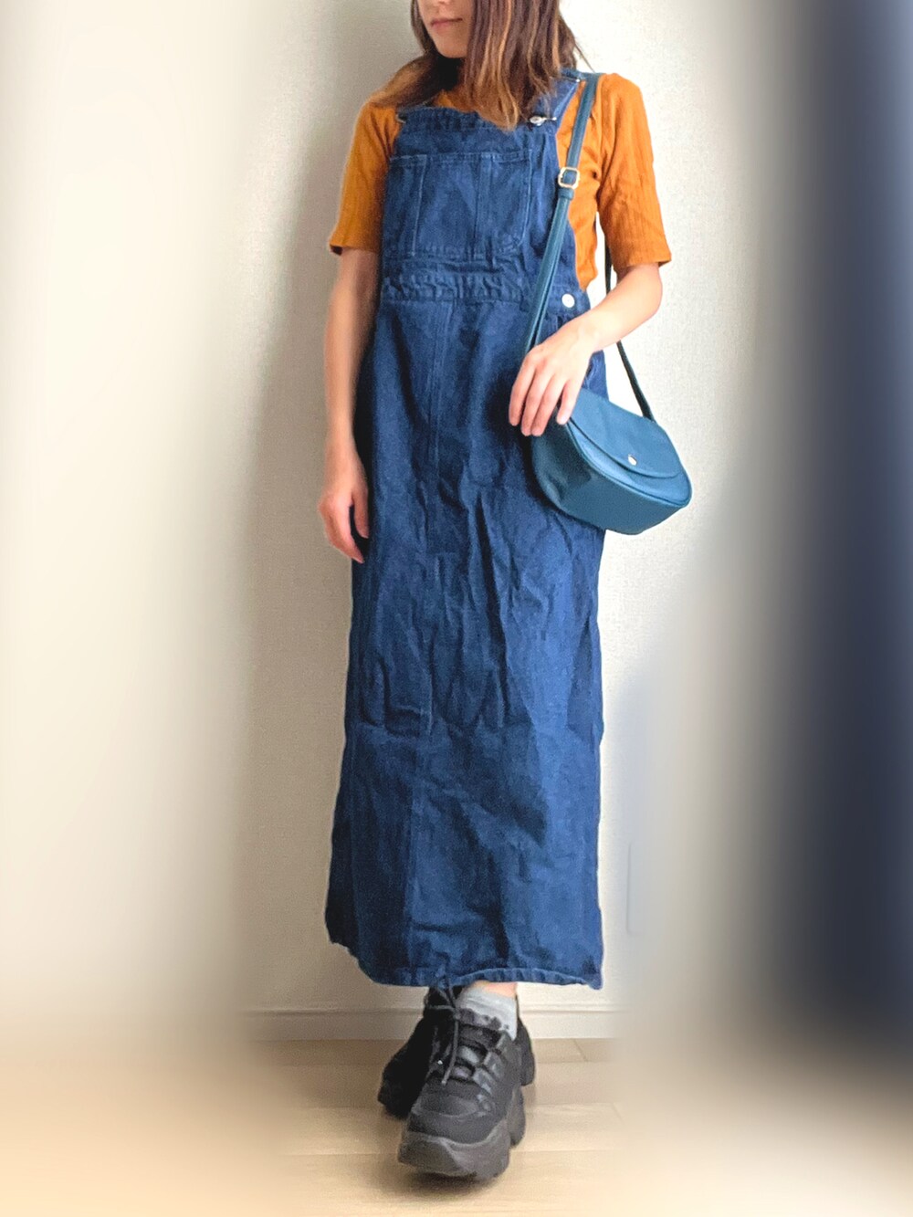 ブルー系のジャンパースカート、ブラック系のスニーカーを着用したレディースの秋コーディネートの2枚目の写真