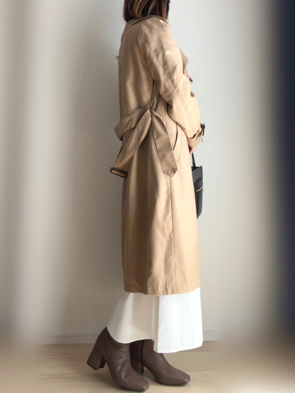 ベージュ系のトレンチコート、ホワイト系のシャツワンピース、ブラウン系のブーツを着用したレディースの冬コーディネートの3枚目の写真