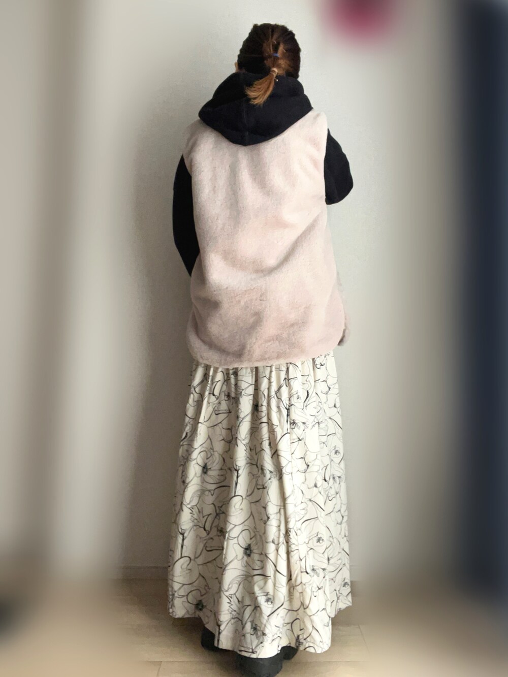 ホワイト系のスカート、ベージュ系のベスト、ブラック系のスニーカーを着用したレディースの冬コーディネートの2枚目の写真