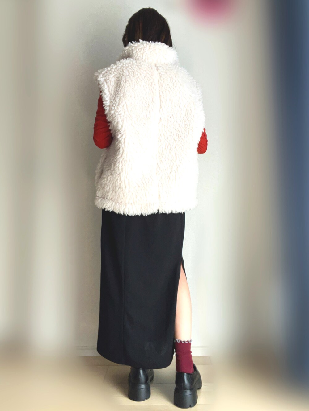 ホワイト系のベスト、オレンジ系のTシャツ/カットソー、ブラック系のワンピースを着用したレディースの冬コーディネートの3枚目の写真