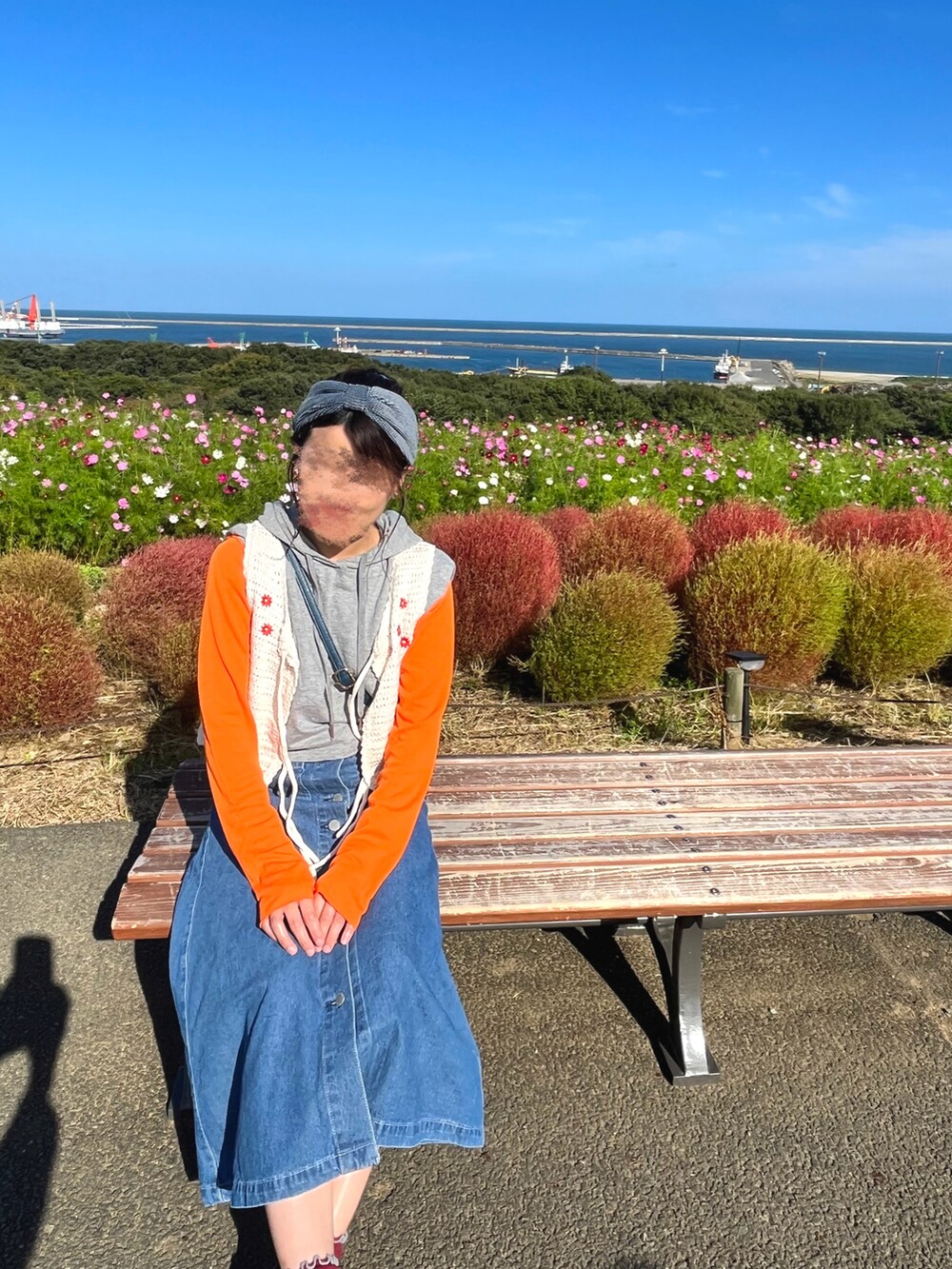 ホワイト系のベスト、ブラック系のスニーカー、ブルー系のデニムスカートを着用したレディースの秋コーディネートの2枚目の写真