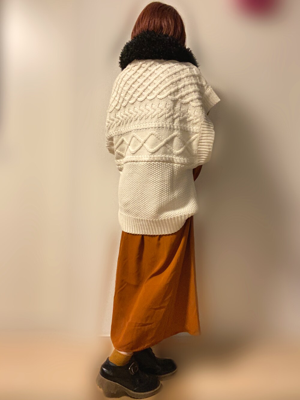 ホワイト系のベスト、オレンジ系のワンピースを着用したレディースの冬コーディネートの2枚目の写真