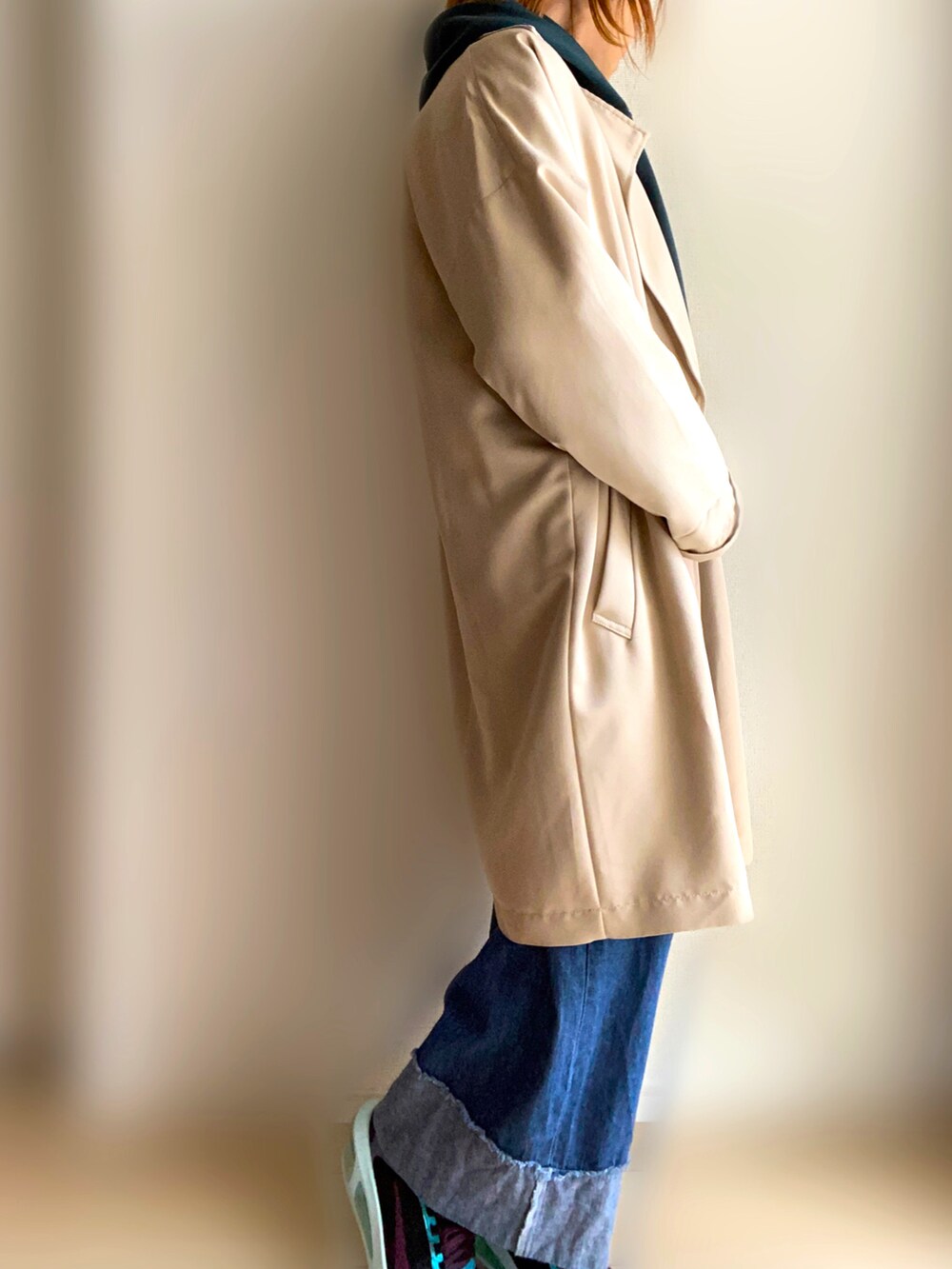 ベージュ系のトレンチコート、グリーン系のパーカー、ブルー系のデニムパンツを着用したレディースの春コーディネートの2枚目の写真