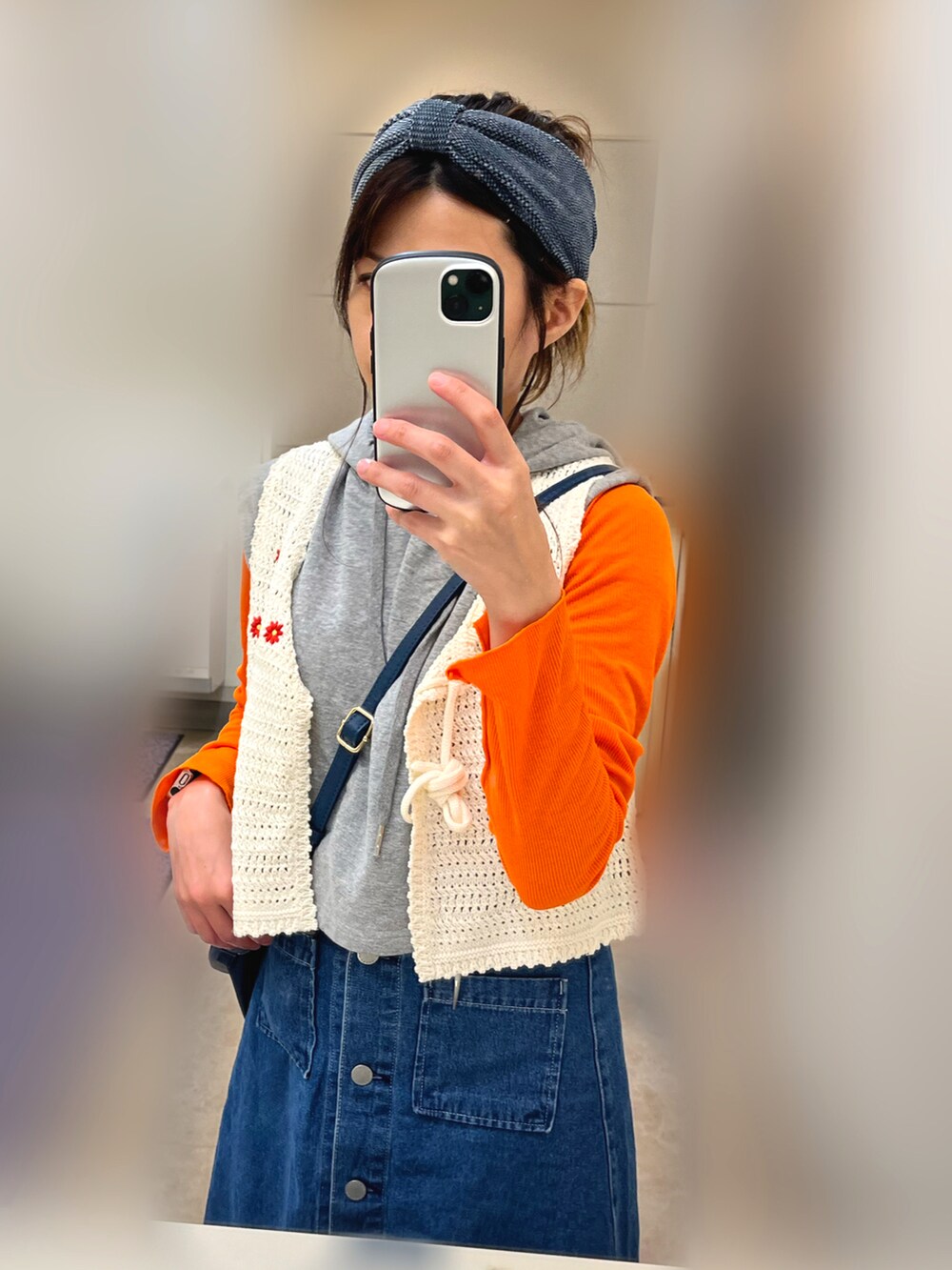 ホワイト系のベスト、ブラック系のスニーカー、ブルー系のデニムスカートを着用したレディースの秋コーディネートの3枚目の写真