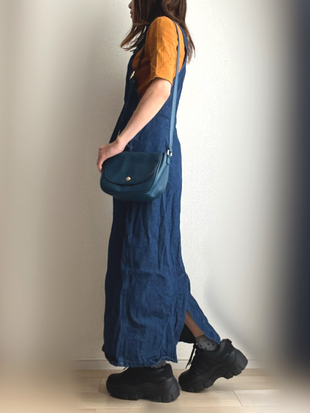 ブルー系のジャンパースカート、ブラック系のスニーカーを着用したレディースの秋コーディネートの3枚目の写真