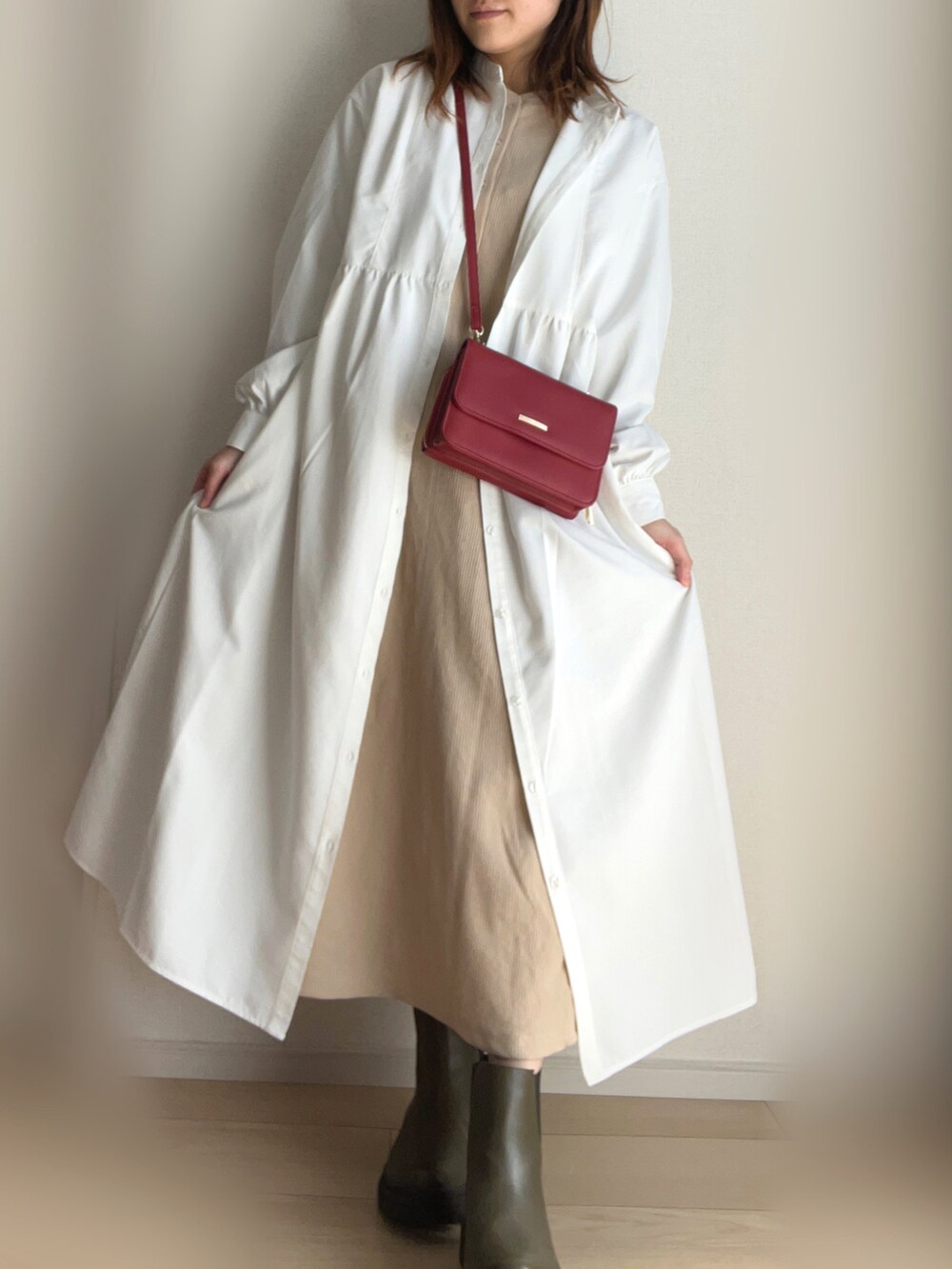 ホワイト系のシャツワンピース、ベージュ系のワンピース、グリーン系のブーツを着用したレディースの春コーディネートの2枚目の写真