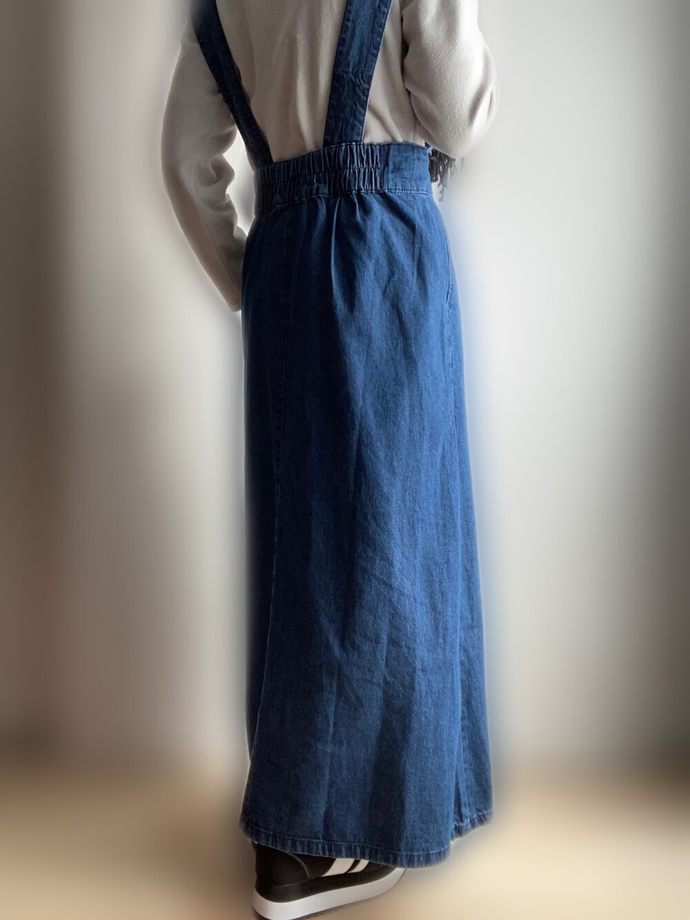 ブルー系のジャンパースカート、ブラック系のスニーカーを着用したレディースの冬コーディネートの3枚目の写真