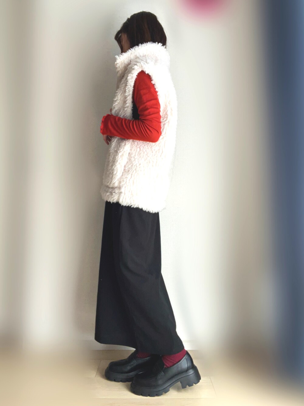 ホワイト系のベスト、オレンジ系のTシャツ/カットソー、ブラック系のワンピースを着用したレディースの冬コーディネートの2枚目の写真