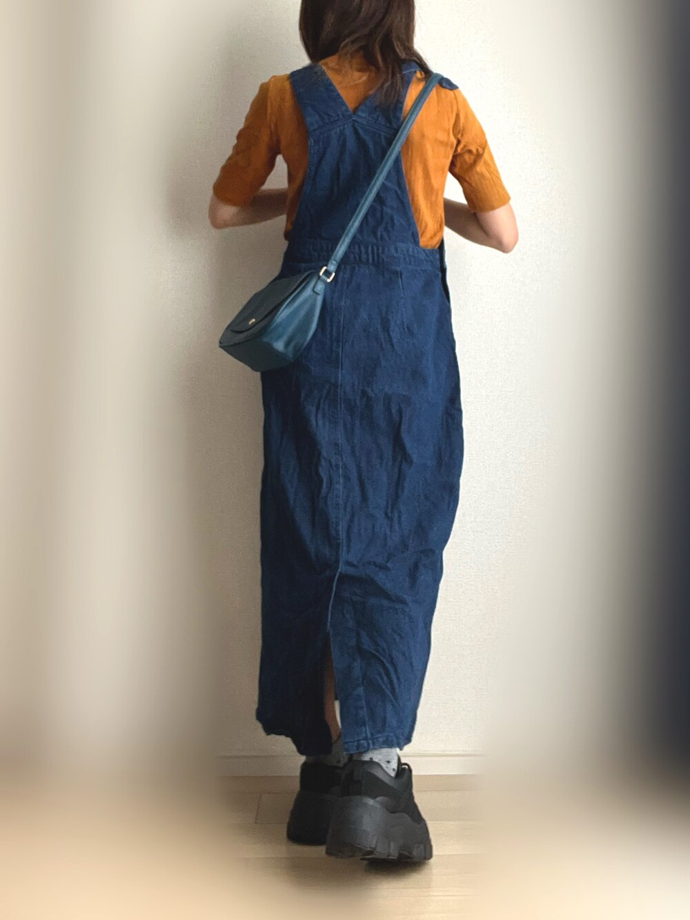 ブルー系のジャンパースカート、ブラック系のスニーカーを着用したレディースの秋コーディネートの4枚目の写真