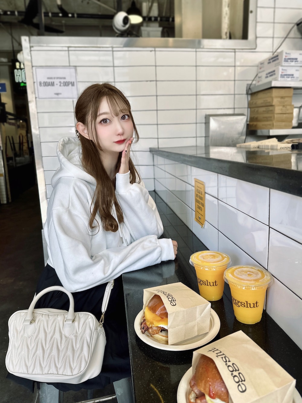 ホワイト系のパーカー、ブラウン系のスニーカー、ブラック系のワンピースを着用したレディースの秋コーディネートの3枚目の写真