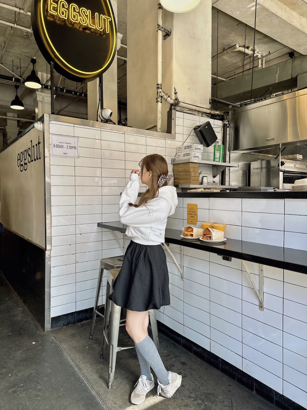 ホワイト系のパーカー、ブラウン系のスニーカー、ブラック系のワンピースを着用したレディースの秋コーディネートの2枚目の写真