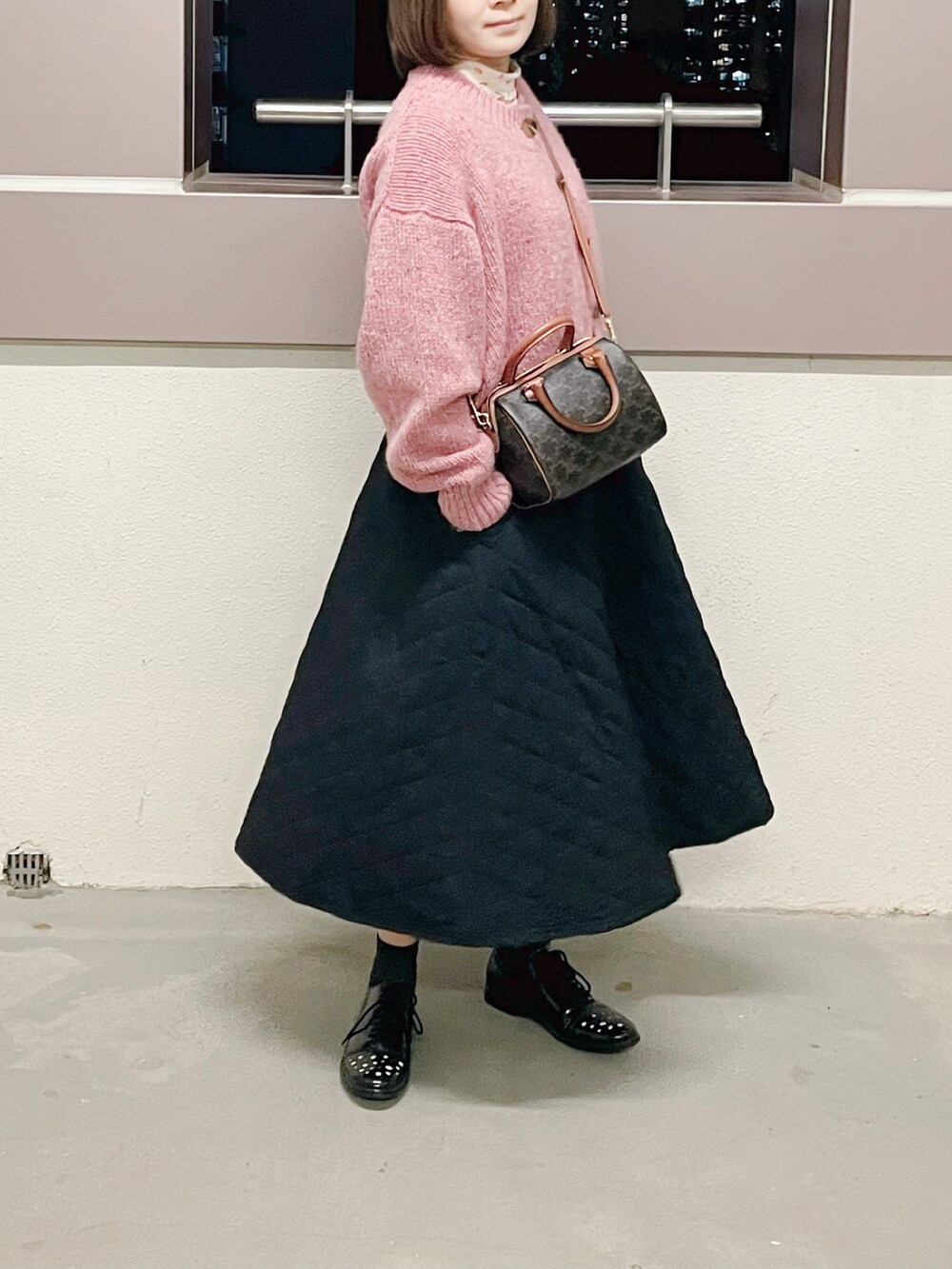 ブラウン系のバッグ、ブラック系のスカート、ピンク系のニット/セーターを着用したレディースの冬コーディネートの2枚目の写真