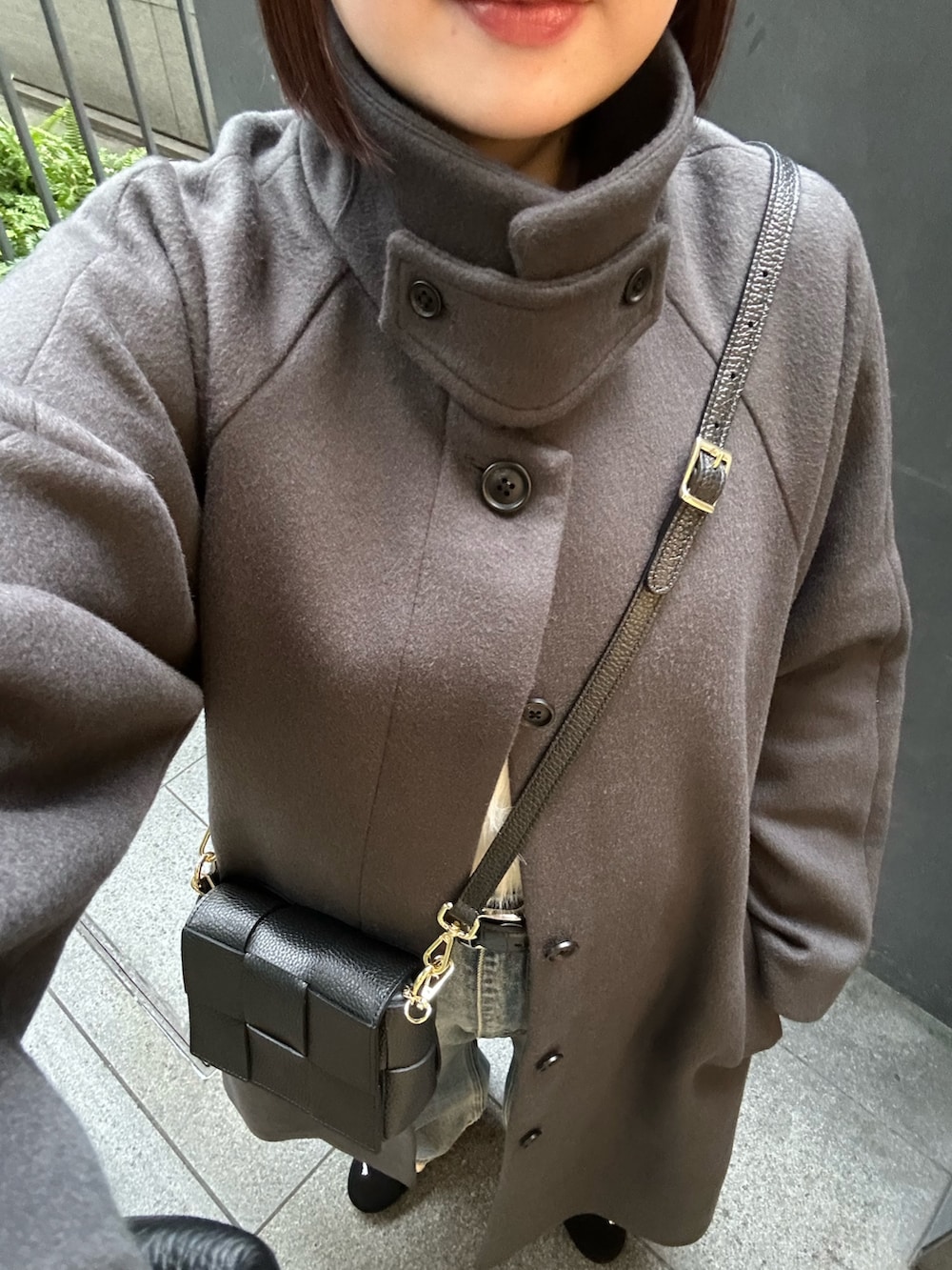 グレー系のステンカラーコート、ホワイト系のニット/セーター、ブルー系のデニムパンツを着用したレディースの秋コーディネートの7枚目の写真