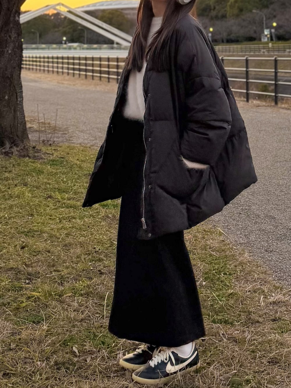 ブラック系のダウンジャケット/コート、ホワイト系のニット/セーター、ブラック系のスカートを着用したレディースの冬コーディネートの2枚目の写真