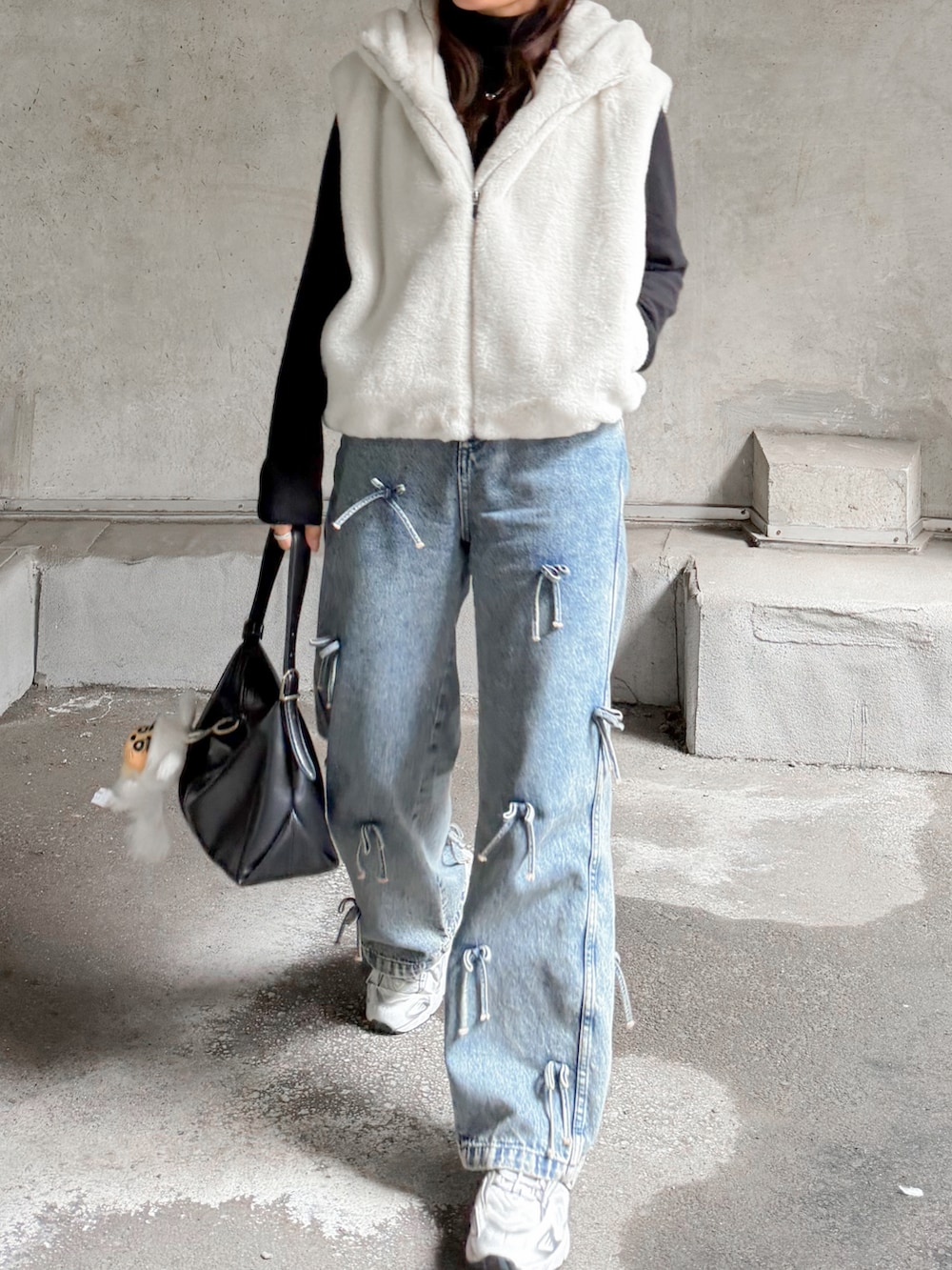 ホワイト系のその他アウター、ブラック系のニット/セーター、ブルー系のデニムパンツを着用したレディースの秋コーディネートの5枚目の写真