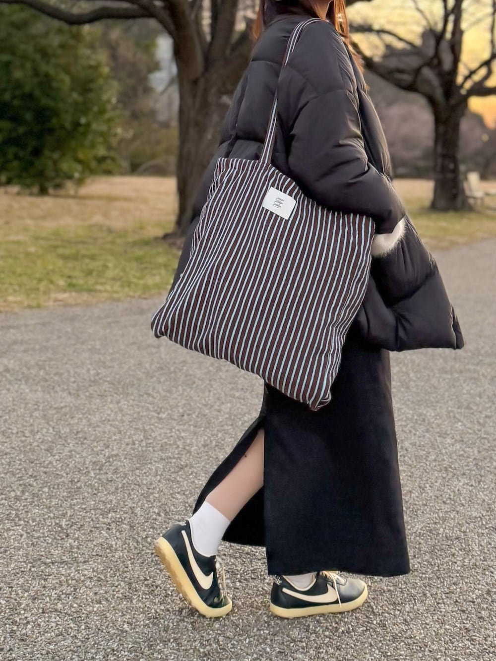 ブラック系のダウンジャケット/コート、ホワイト系のニット/セーター、ブラック系のスカートを着用したレディースの冬コーディネートの5枚目の写真