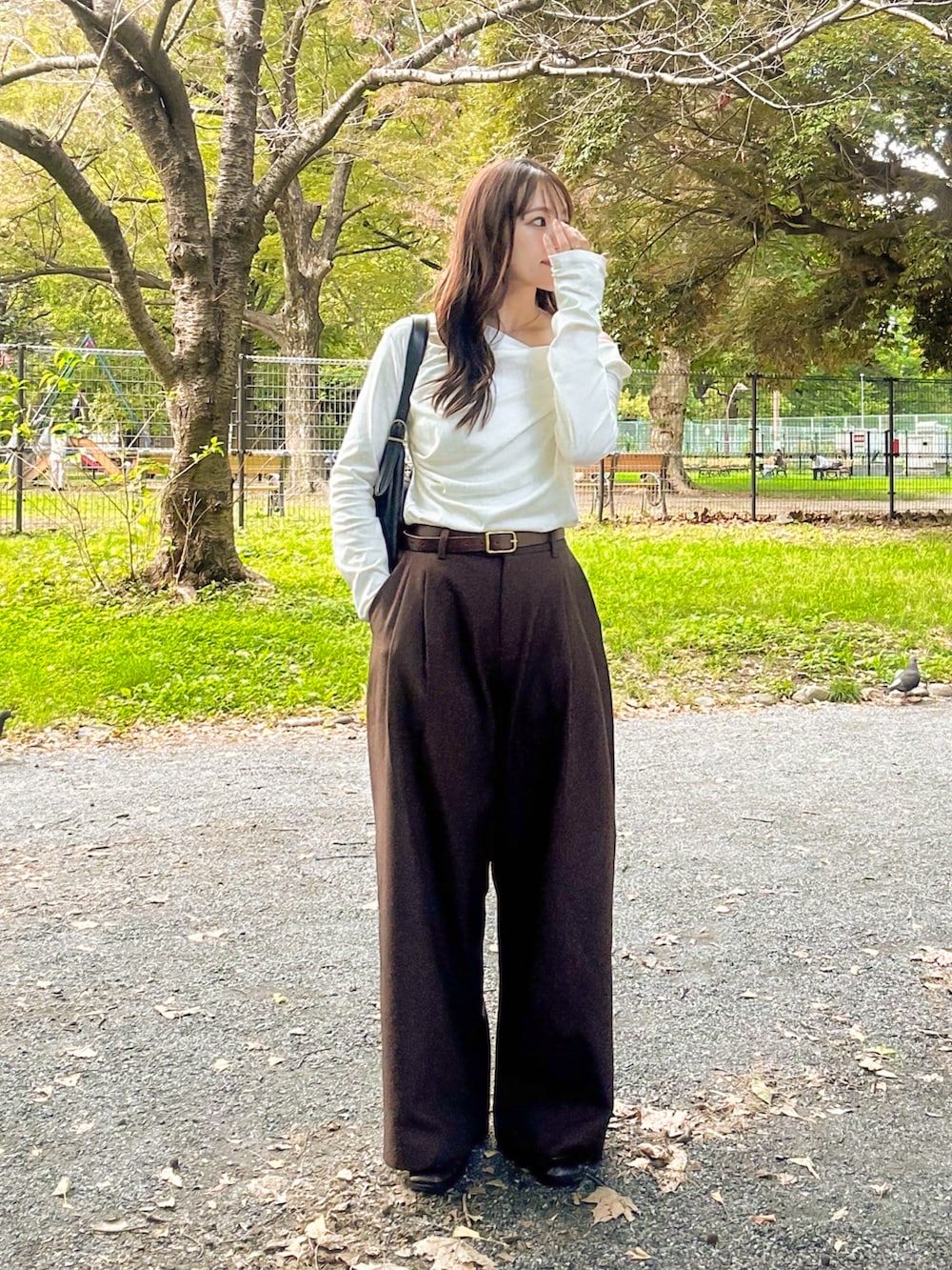 ホワイト系のTシャツ/カットソー、ブラウン系のスラックス、ブラック系のショルダーバッグを着用したレディースの秋コーディネートの4枚目の写真