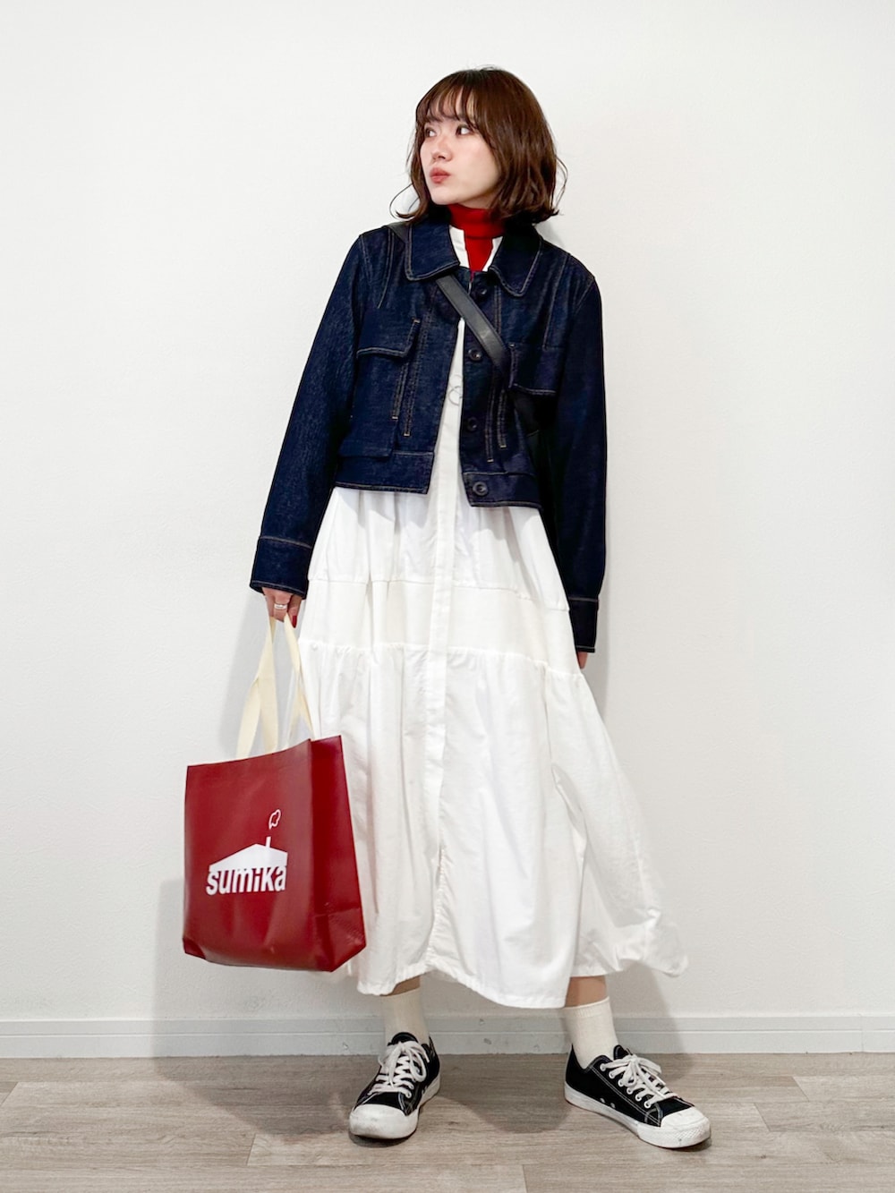 レッド系のニット/セーター、ホワイト系のワンピース、ブルー系のデニムジャケットを着用したレディースの冬コーディネートの2枚目の写真