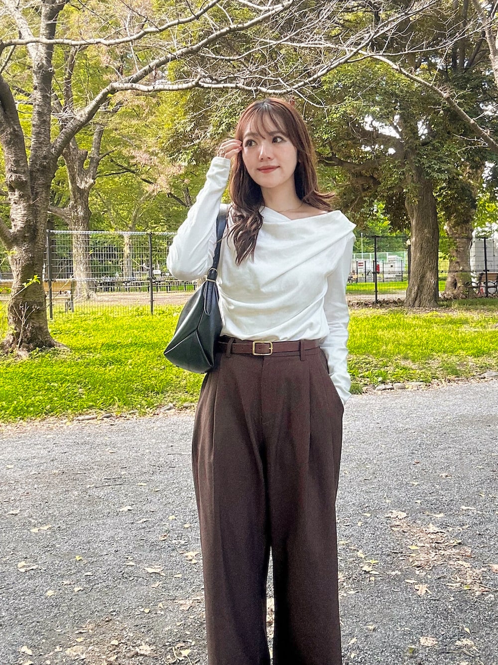 ホワイト系のTシャツ/カットソー、ブラウン系のスラックス、ブラック系のショルダーバッグを着用したレディースの秋コーディネートの3枚目の写真