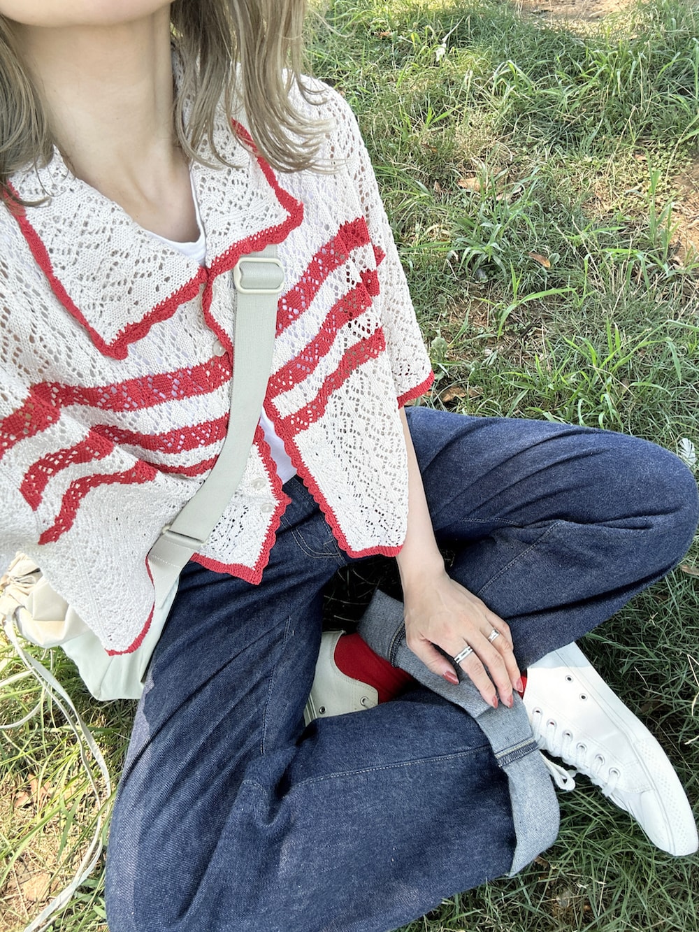 ホワイト系のニット/セーター、ホワイト系のタンクトップ、ブルー系のデニムパンツを着用したレディースの夏コーディネートの3枚目の写真