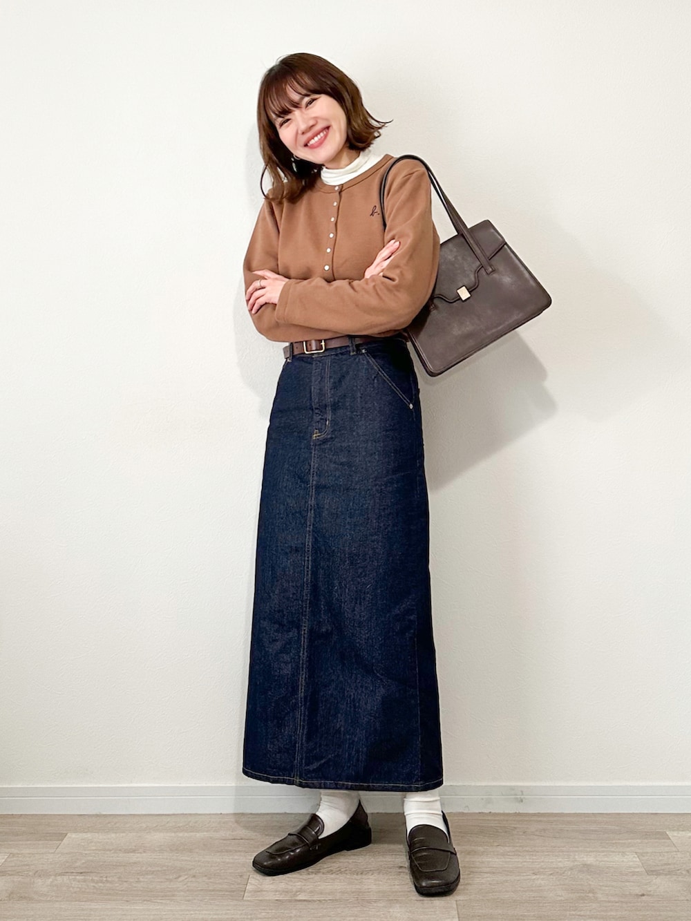 ブラウン系のカーディガン/ボレロ、ホワイト系のTシャツ/カットソー、ブルー系のデニムスカートを着用したレディースの冬コーディネートの3枚目の写真
