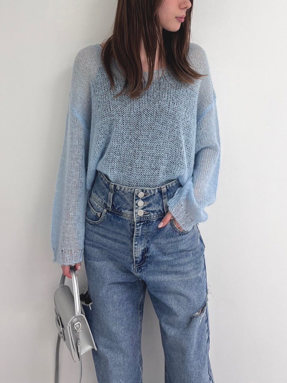 ブルー系のデニムパンツ、シルバー系のショルダーバッグ、ホワイト系のブーツを着用したレディースの春コーディネートの3枚目の写真