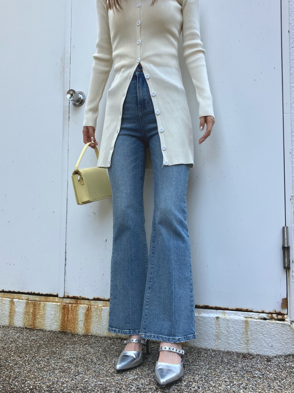 ホワイト系のワンピース、ブルー系のデニムパンツ、シルバー系のパンプスを着用したレディースの冬コーディネートの3枚目の写真