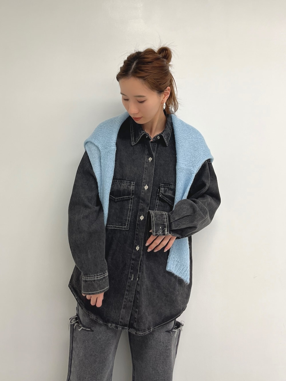 ブラック系のデニムパンツ、ブラック系のシャツ/ブラウス、ブルー系のニット/セーターを着用したレディースの春コーディネートの2枚目の写真