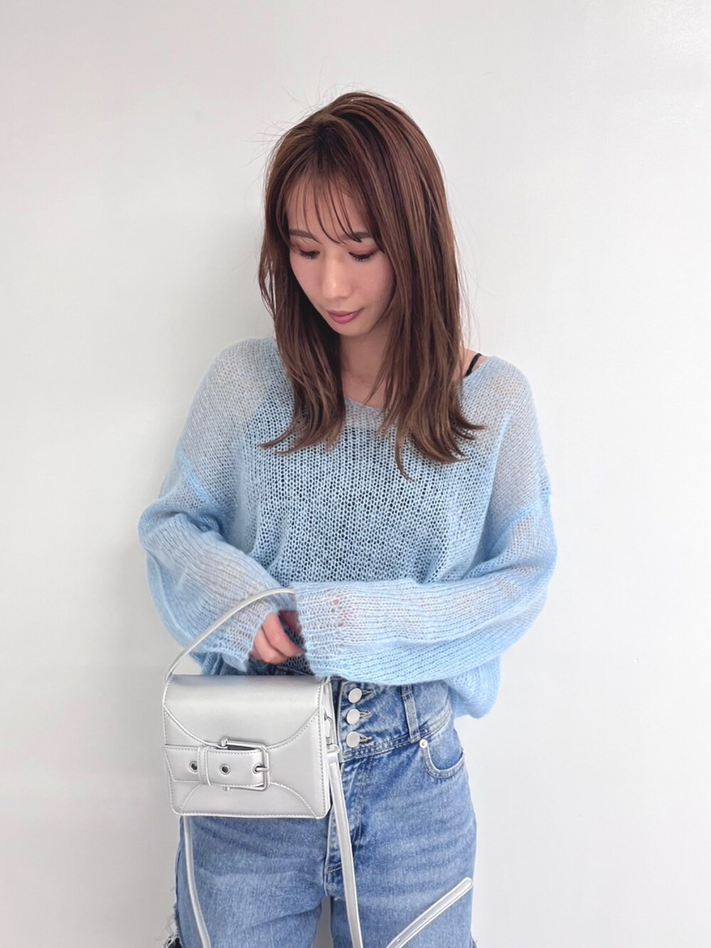 ブルー系のデニムパンツ、シルバー系のショルダーバッグ、ホワイト系のブーツを着用したレディースの春コーディネートの2枚目の写真