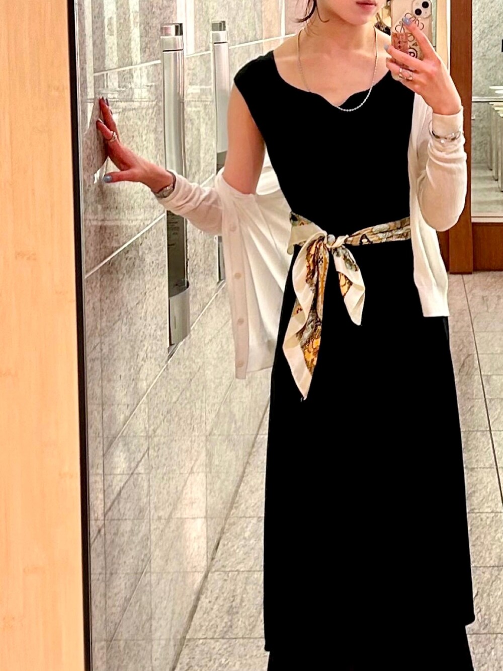 ブラック系のローファー、ブラック系のスカート、ホワイト系のカーディガン/ボレロを着用したレディースの夏コーディネートの2枚目の写真