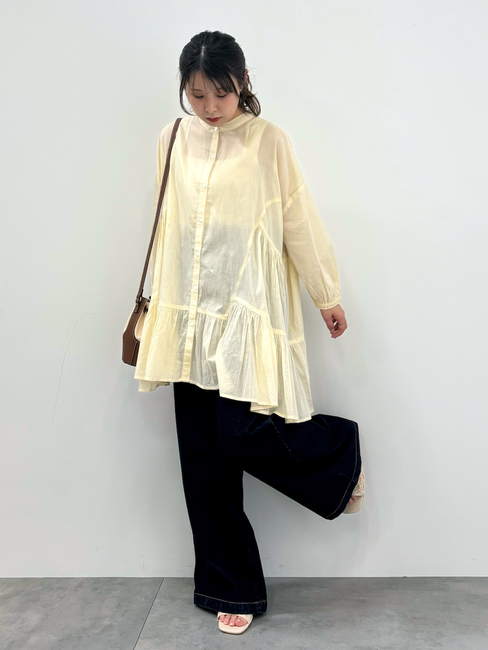 ブルー系のデニムパンツ、ホワイト系のチュニックを着用したレディースの春コーディネートの3枚目の写真