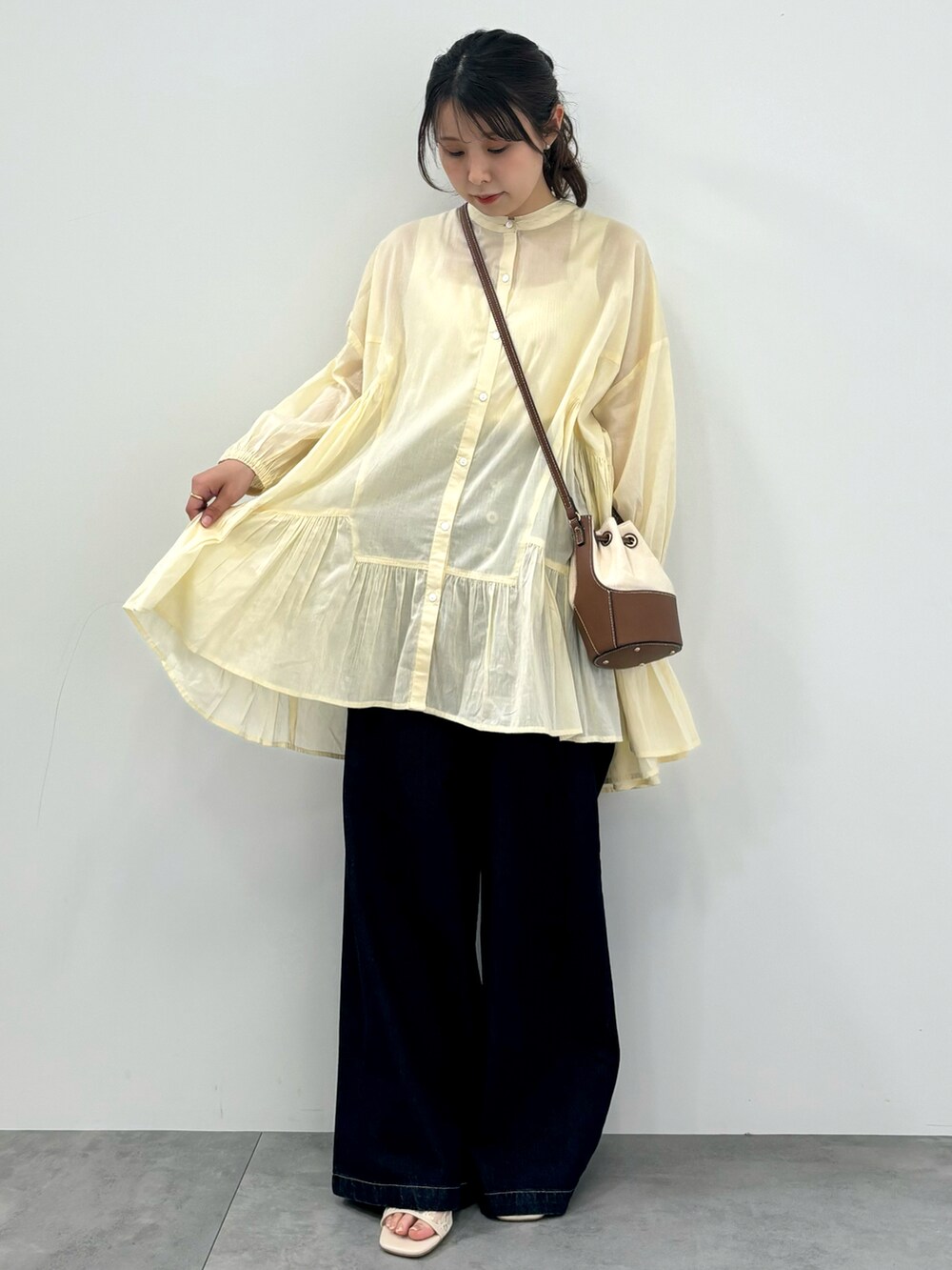 ブルー系のデニムパンツ、ホワイト系のチュニックを着用したレディースの春コーディネートの2枚目の写真