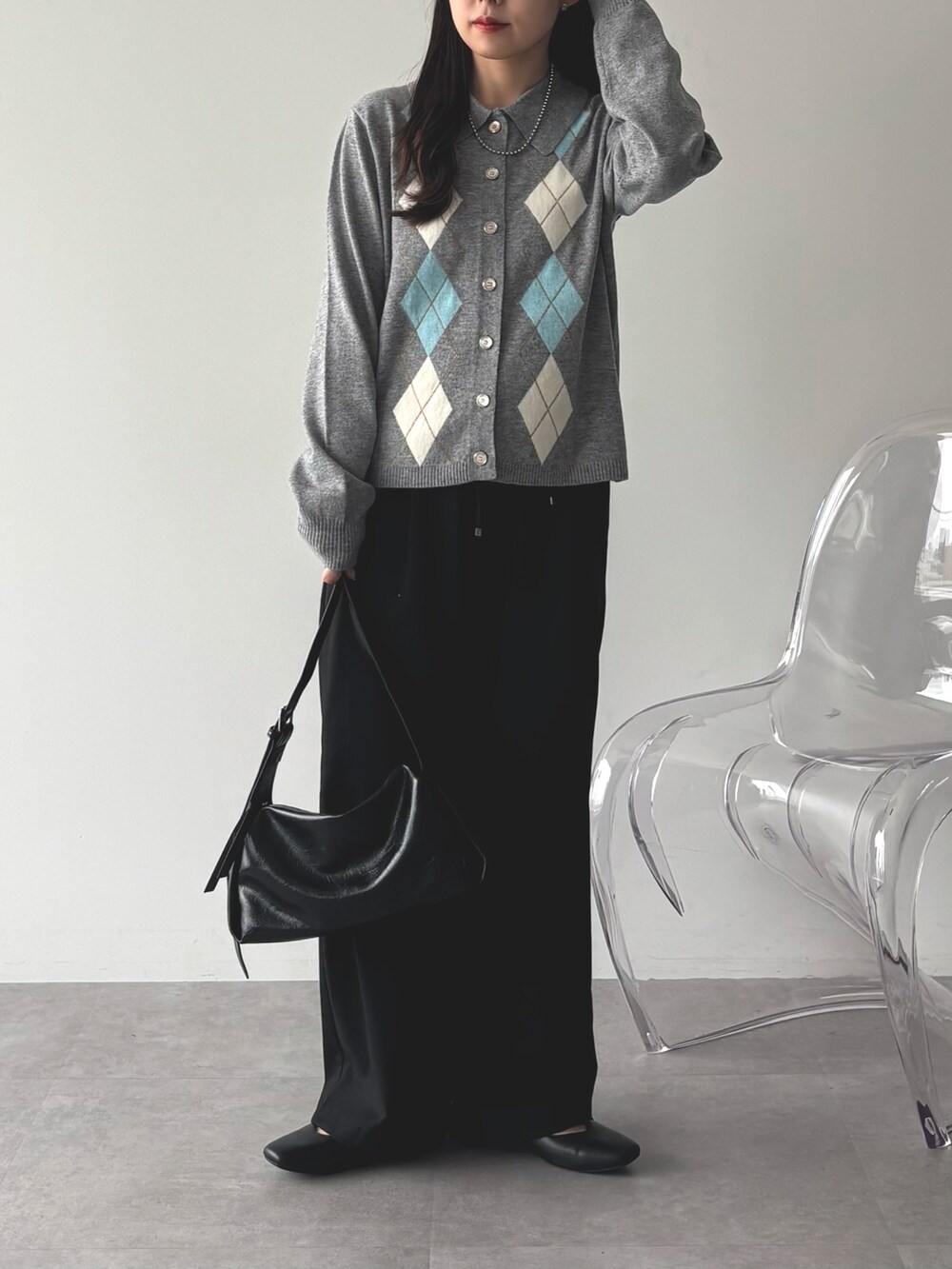 グレー系のニット/セーター、ブラック系のパンプス、ブラック系のショルダーバッグを着用したレディースの秋コーディネートの2枚目の写真