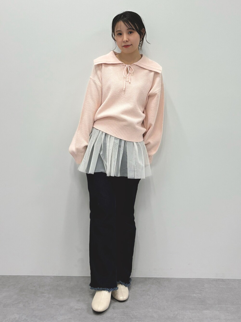 ピンク系のニット/セーター、ブルー系のデニムパンツ、ホワイト系のチュニックを着用したレディースの春コーディネートの2枚目の写真