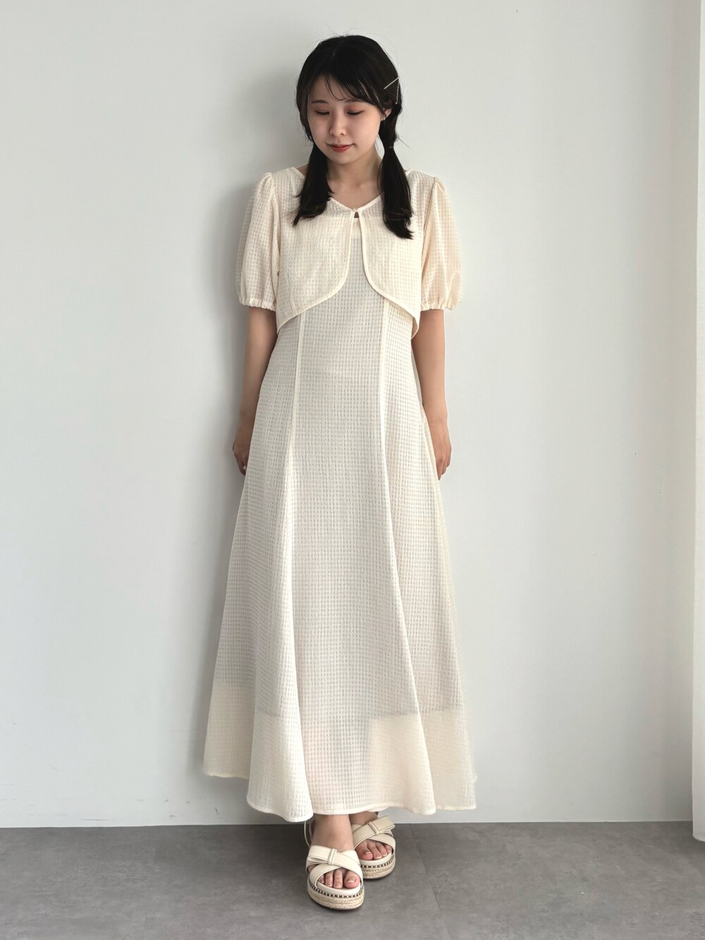 ホワイト系のワンピース、ベージュ系のサンダルを着用したレディースの春コーディネートの2枚目の写真