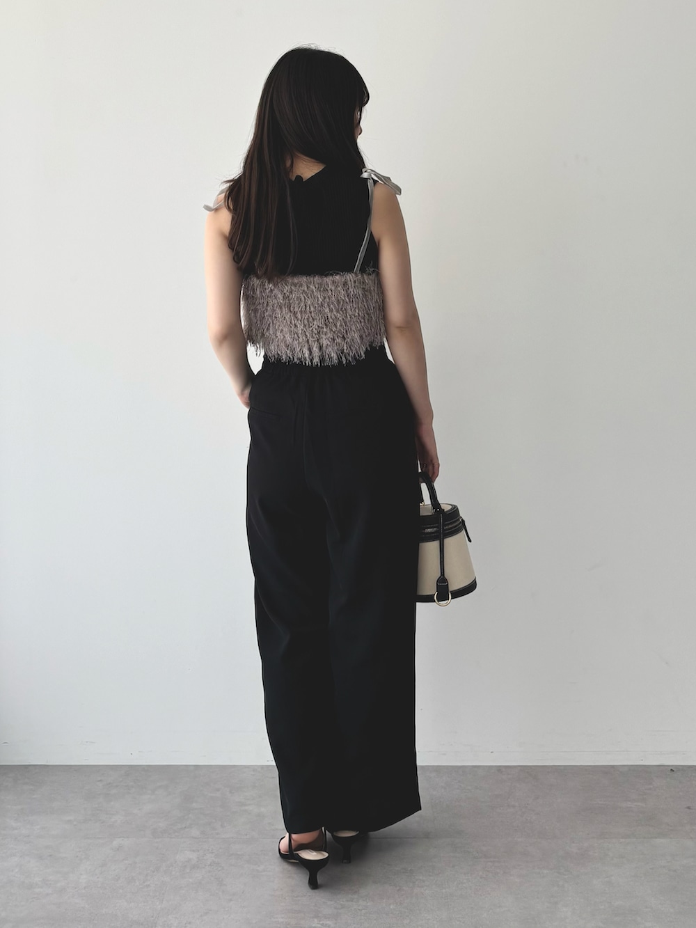 ブラウン系のベスト、ブラック系のスラックス、ブラック系のニット/セーターを着用したレディースの夏コーディネートの2枚目の写真