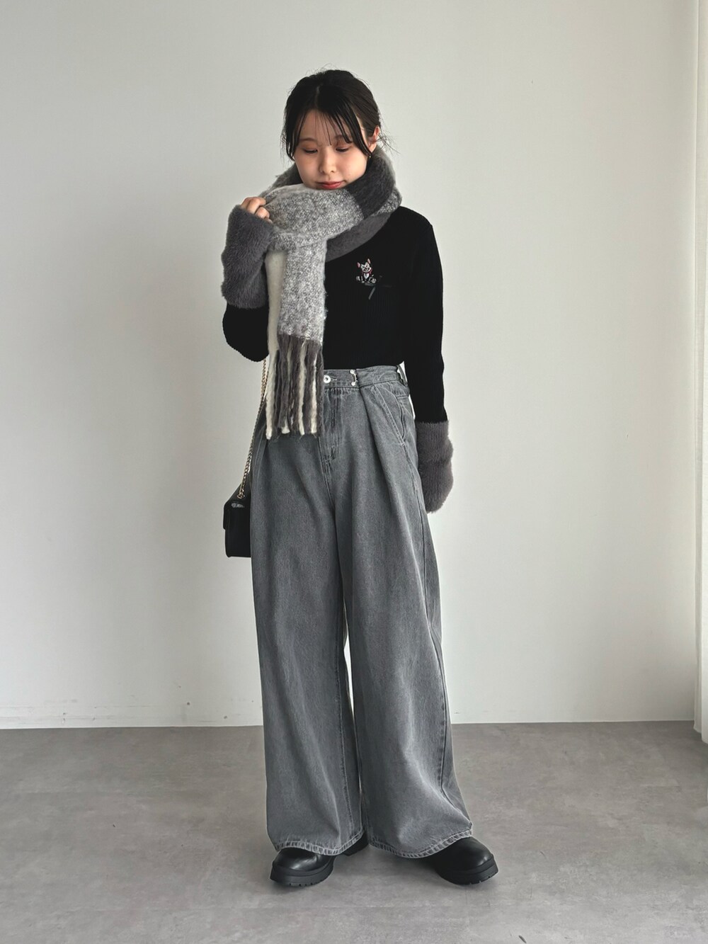 ブラック系のニット/セーター、グレー系のデニムパンツ、ブラック系のマフラーを着用したレディースの秋コーディネートの3枚目の写真