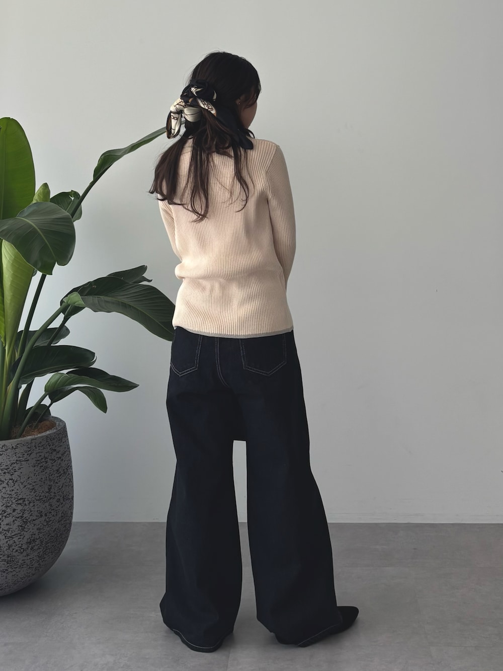 ホワイト系のニット/セーター、ブラック系のデニムパンツ、ブラック系のバンダナ/スカーフを着用したレディースの秋コーディネートの3枚目の写真