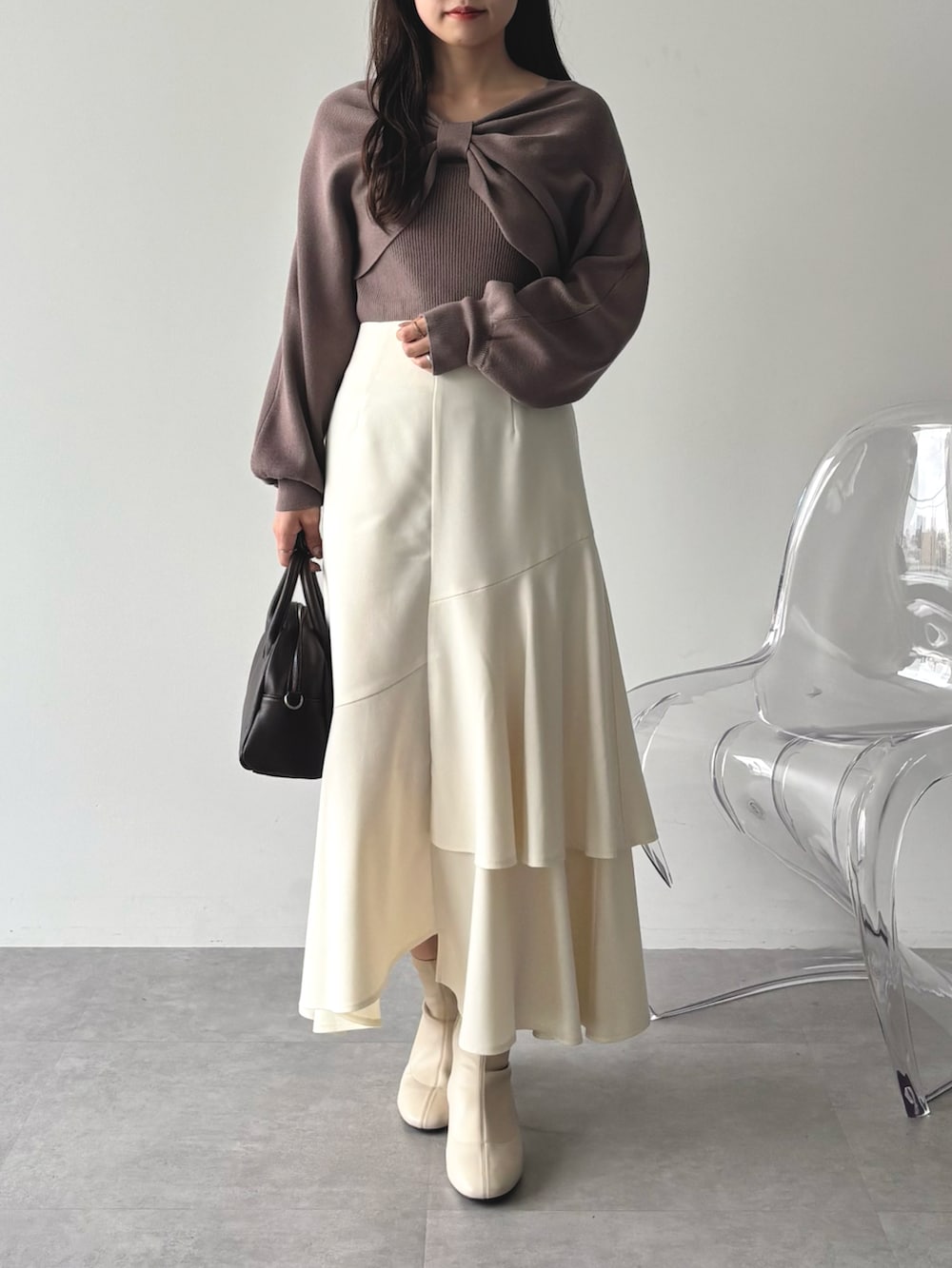 ブラウン系のニット/セーター、ホワイト系のスカートを着用したレディースの秋コーディネートの2枚目の写真