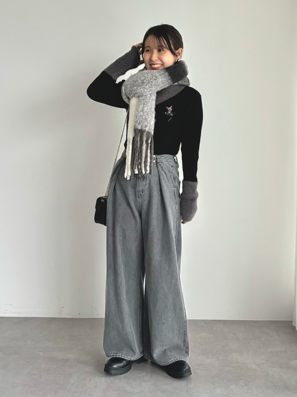 ブラック系のニット/セーター、グレー系のデニムパンツ、ブラック系のマフラーを着用したレディースの秋コーディネートの2枚目の写真