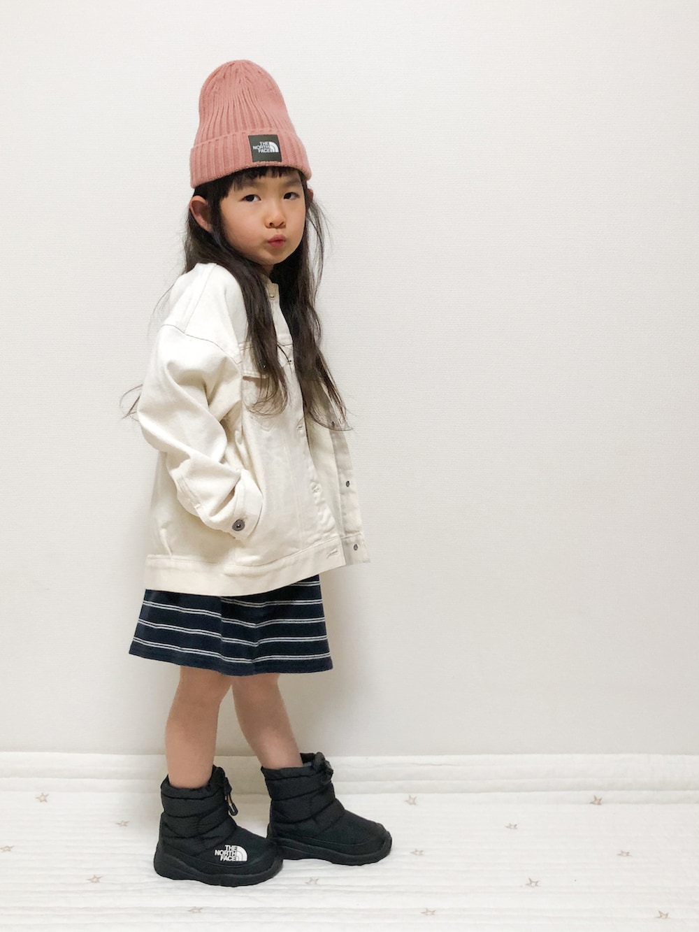 ホワイト系のデニムジャケット、ブラック系のブーツ、ピンク系のキャップを着用したキッズの春コーディネートの2枚目の写真