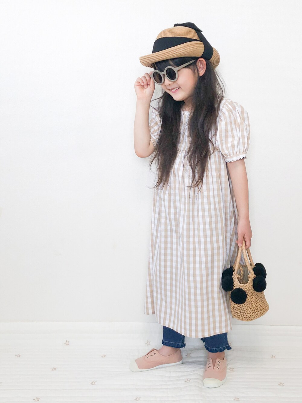 ベージュ系のシャツワンピース、ベージュ系のデニムパンツを着用したキッズの夏コーディネートの3枚目の写真